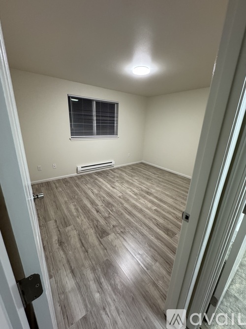 A room with wooden flooring and a window with blinds.