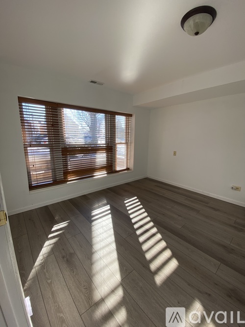 A room with wooden flooring and a window with blinds.