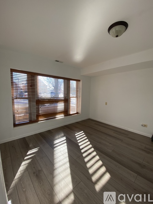 A room with wooden floors and a window with blinds.