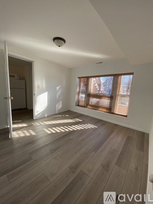 A room with wooden flooring and a window with blinds.