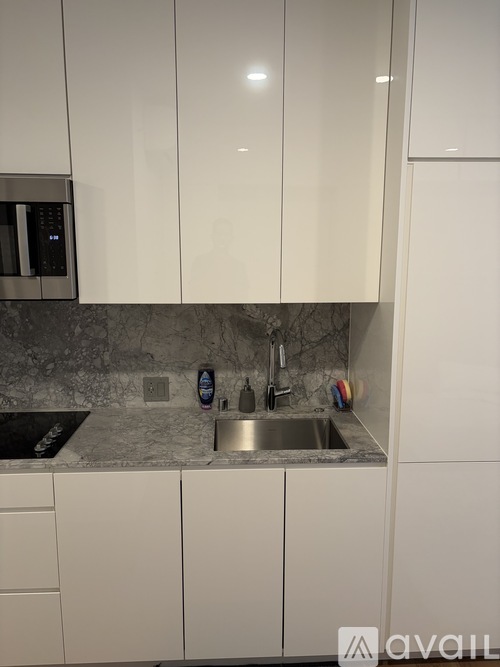 A kitchen with white cabinets and a marble countertop.