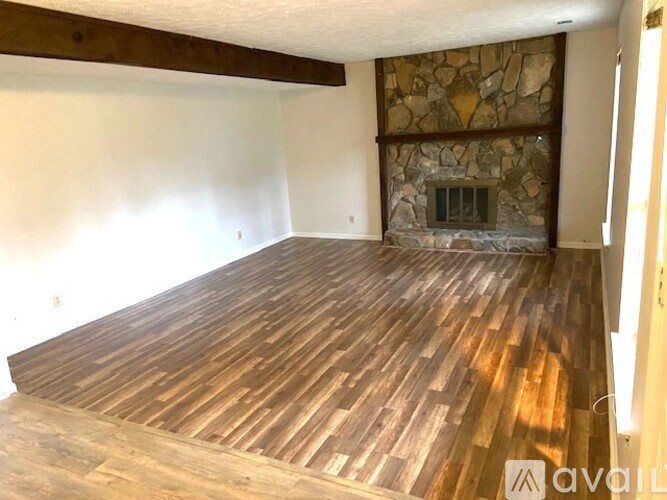 A room with wooden flooring and a stone fireplace.