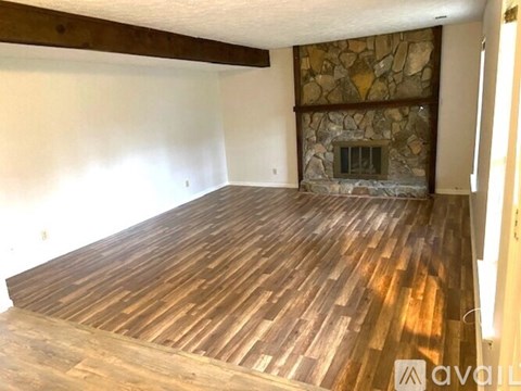A room with wooden flooring and a stone fireplace.