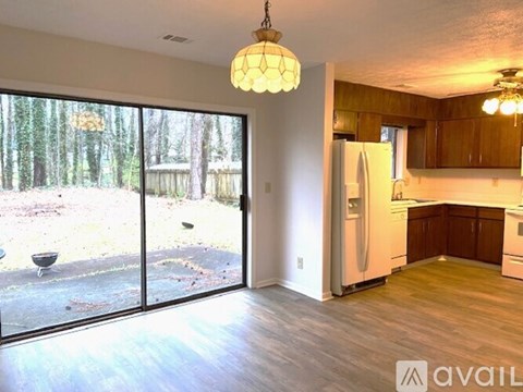 A kitchen with a refrigerator, cabinets, and a dining table is available for rent.