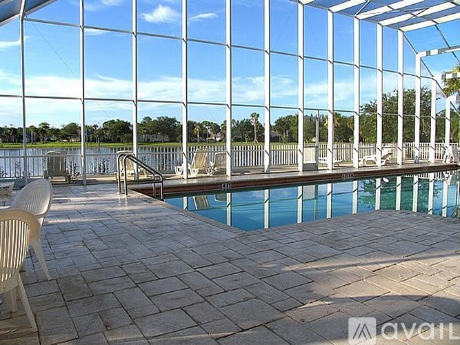 A pool area with a glass wall overlooking a lake.