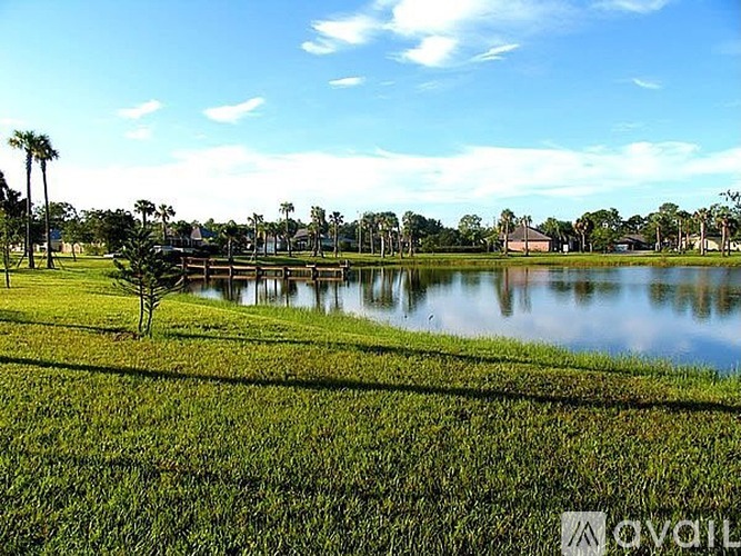 A grassy field with a body of water and trees in the background.