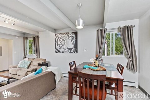 A living room with a couch, a dining table, and a painting of a tiger on the wall.