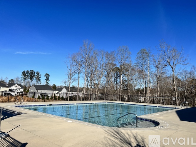 A large outdoor swimming pool surrounded by trees and a residential area.