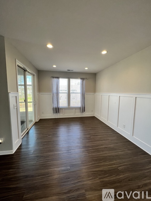 A spacious room with wooden floors and white walls.