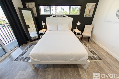 A bedroom with a large bed and a balcony with a view of the trees.