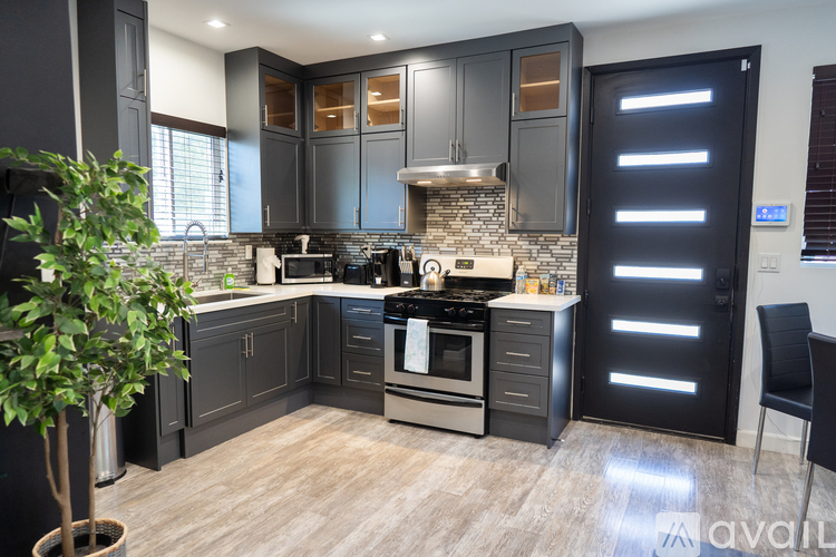 A modern kitchen with dark wood cabinets and a stone backsplash.
