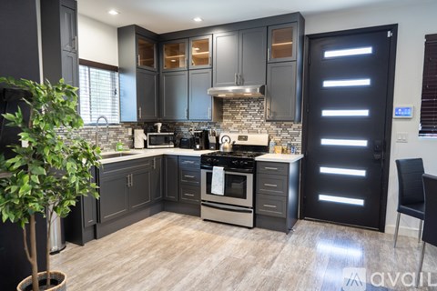 A modern kitchen with dark wood cabinets and a stone backsplash.