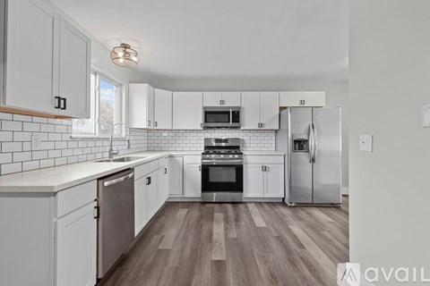 A kitchen with white cabinets and a wooden floor.