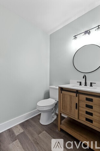 A bathroom with a toilet, sink, and mirror.