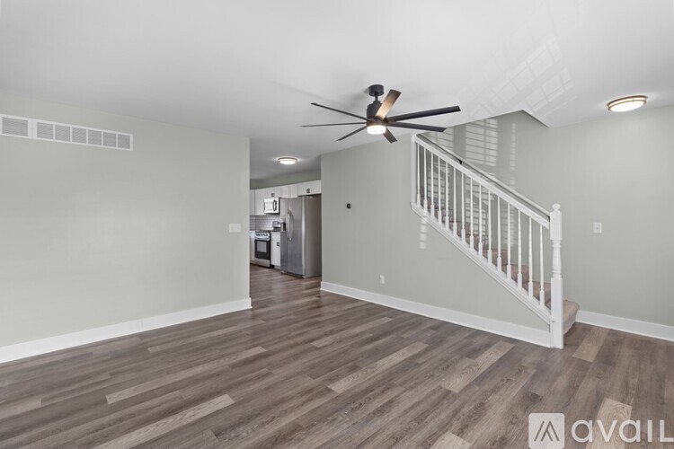 A spacious room with a wood floor and a ceiling fan.