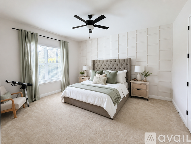 A bedroom with a large bed, a ceiling fan, and a chair.
