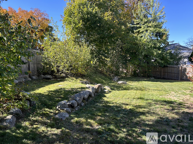 A backyard with a stone wall and green grass.