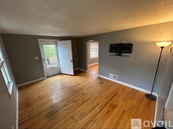 A room with wooden floors and a flat screen TV mounted on the wall.