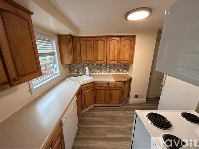 A kitchen with wooden cabinets and a white stove top oven.