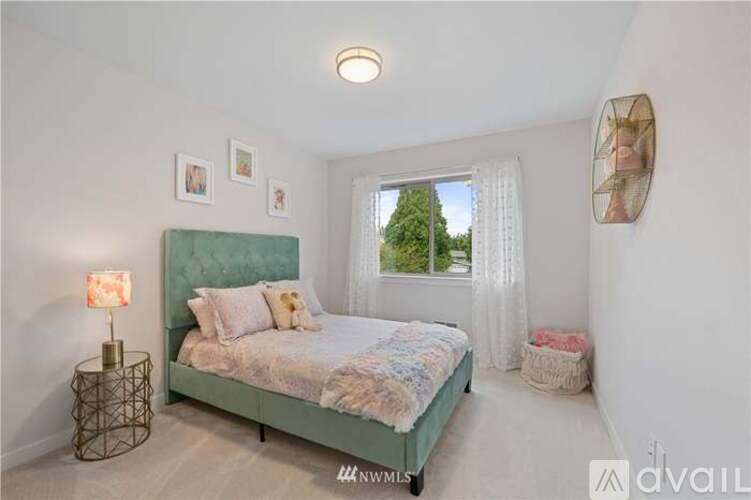 A bedroom with a green bed and a window with white curtains.