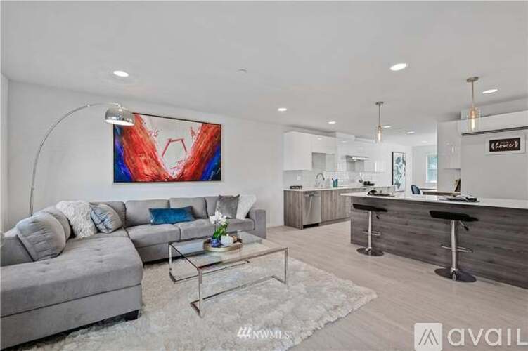 A modern living room with a grey sofa, a glass coffee table, and a large abstract painting on the wall.