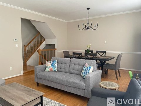 A living room with a grey couch and a wooden staircase.