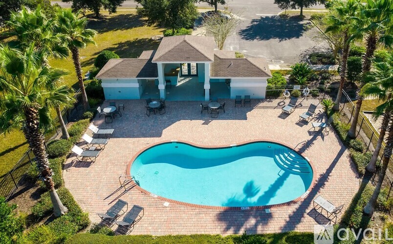 A pool surrounded by chairs and a house with a pool house.