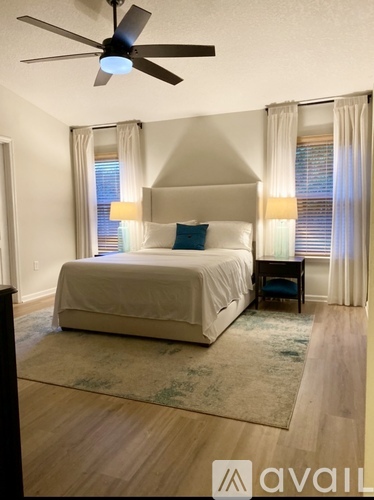 A bedroom with a bed, a ceiling fan, and a rug.
