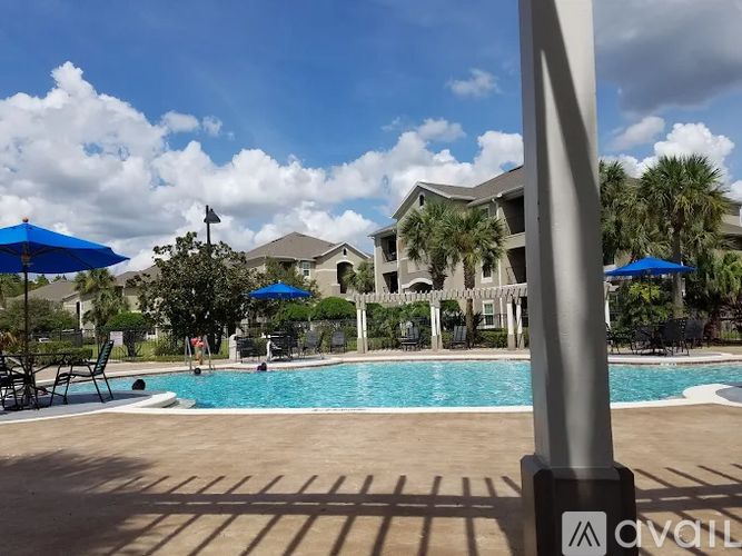 A pool area with a blue umbrella and a building in the background.
