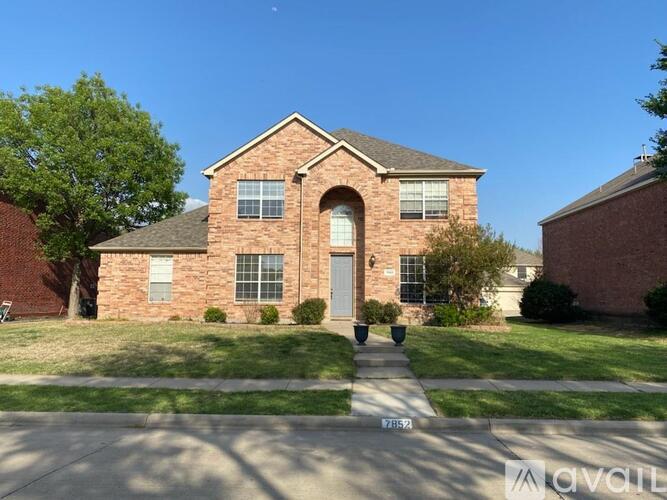 A brick house with a front yard and a driveway.