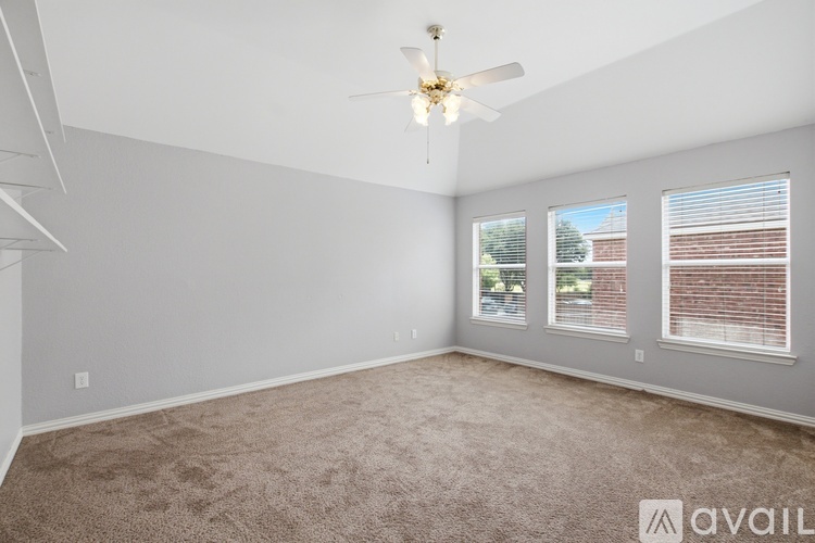 A spacious room with a carpeted floor and a ceiling fan.