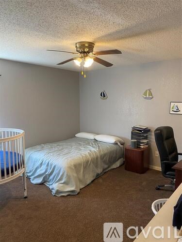 A bedroom with a bed, chair, and a ceiling fan.