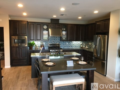 A modern kitchen with dark wood cabinets and stainless steel appliances.