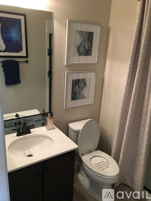 A bathroom with a toilet, sink, and pictures on the wall.