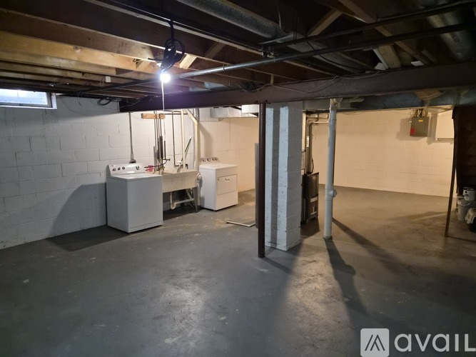 A spacious basement with concrete floors and exposed ceiling beams.