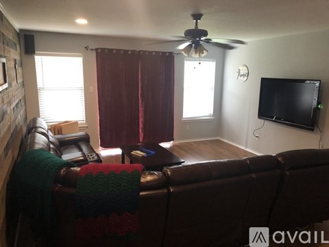 A living room with a brown couch and a ceiling fan.