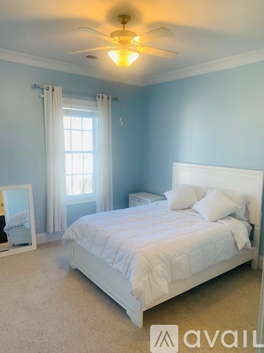 A bedroom with a white bed and a ceiling fan.