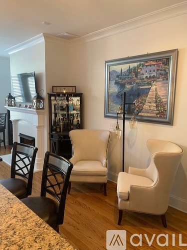 A living room with a painting of a town on the wall.