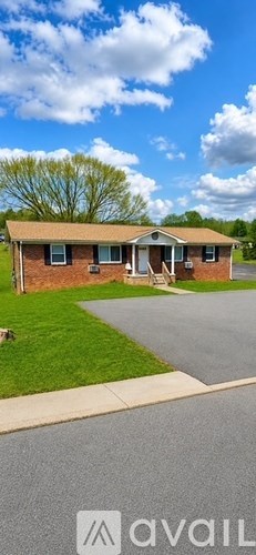A house with a brown roof and a white door is surrounded by a grassy lawn.