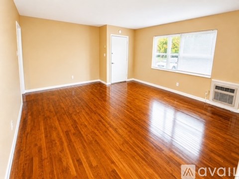 A room with wooden floors and a window with blinds.