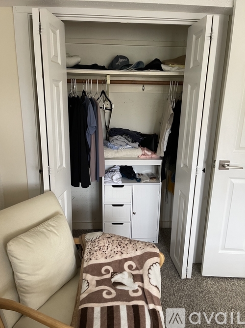 A small bedroom with a bed under the closet and a chair.
