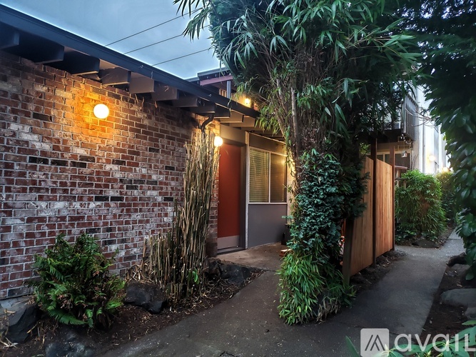 A small building with a red door surrounded by greenery.