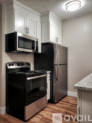A kitchen with a black oven and stove top, a black microwave, and a silver refrigerator.