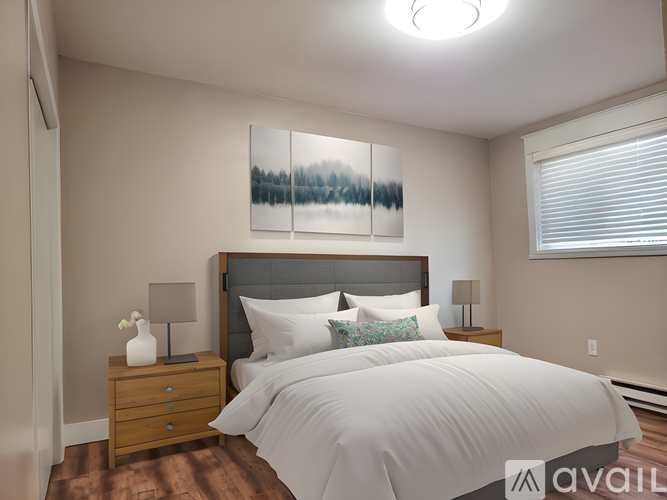 A bedroom with a large bed, a nightstand with a lamp, and a painting on the wall.