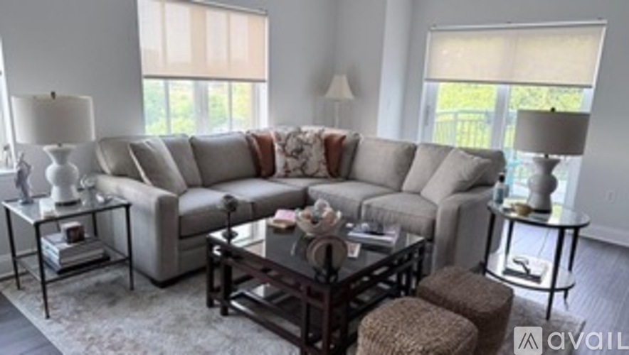A living room with a grey couch and a glass table.