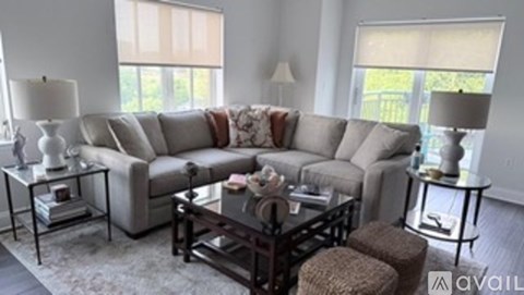 A living room with a grey couch and a glass table.