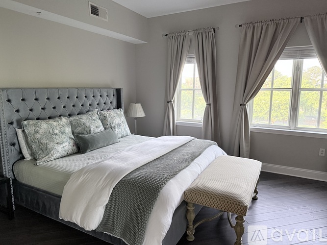 A bedroom with a large bed and a window with curtains.