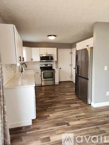 A kitchen with white cabinets and a wooden floor.