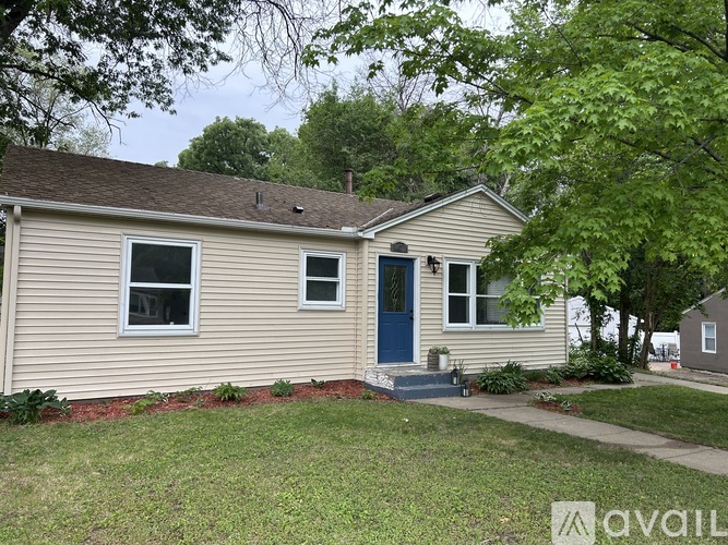 A beige house with a blue door and a small front yard.