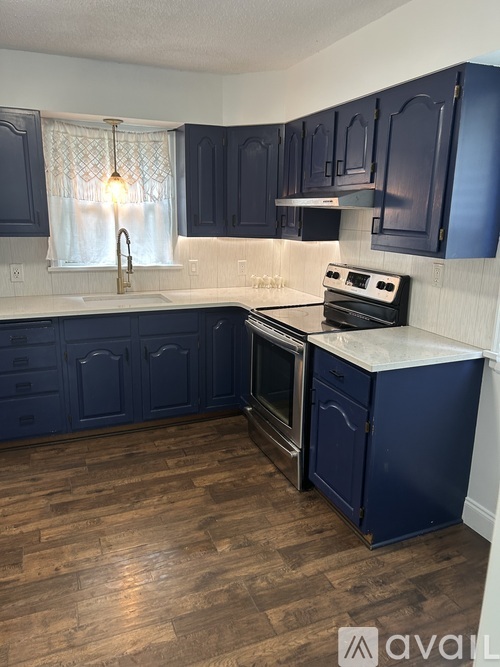 A kitchen with dark blue cabinets and a wooden floor.